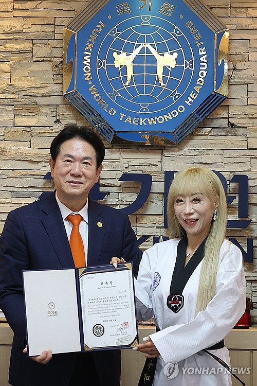 South Korean soprano Jo Su-mi (R) poses for a photo with Lee Dong-sup, head of the World Taekwondo Headquarters, during a ceremony in Seoul on April 18, 2025, to mark her appointment as a promotional ambassador for the headquarters also known as Kukkiwon. (Yonhap) (END)