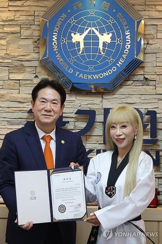 South Korean soprano Jo Su-mi (R) poses for a photo with Lee Dong-sup, head of the World Taekwondo Headquarters, during a ceremony in Seoul on April 18, 2025, to mark her appointment as a promotional ambassador for the headquarters also known as Kukkiwon. (Yonhap) (END)