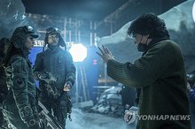 This undated AP photo shows director Bong Joon-ho (R) communicating with actors during the filming of "Mickey 17." (Yonhap)