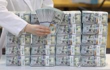 This file photo, taken March 6, 2024, shows a clerk sorting US$100 banknotes at a Seoul bank. (Yonhap)