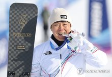 Kim Sang-kyum of South Korea bites the silver medal he won in the men's parallel giant slalom snowboard event at the Winter Olympics at Livigno Snow Park in Livigno, Italy, on Feb. 8, 2026. (Yonhap)