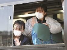 Junior high school students wave to their families from a bus in Wajima, Ishikawa Prefecture, on Jan. 17, 2023, as they leave their badly damaged hometown to study some 100 kilometers away after a powerful earthquake hit the central Japan prefecture. (Kyodo)